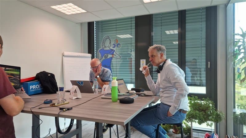 Two men in a modern office having a meeting at a table with laptops.