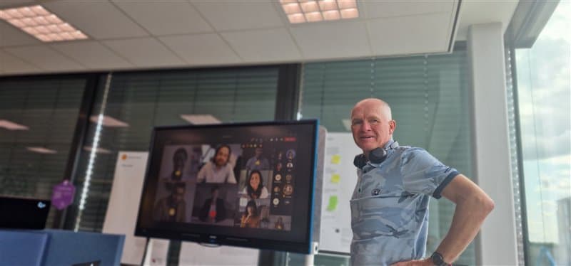 Person in an office with a video call on a large screen.